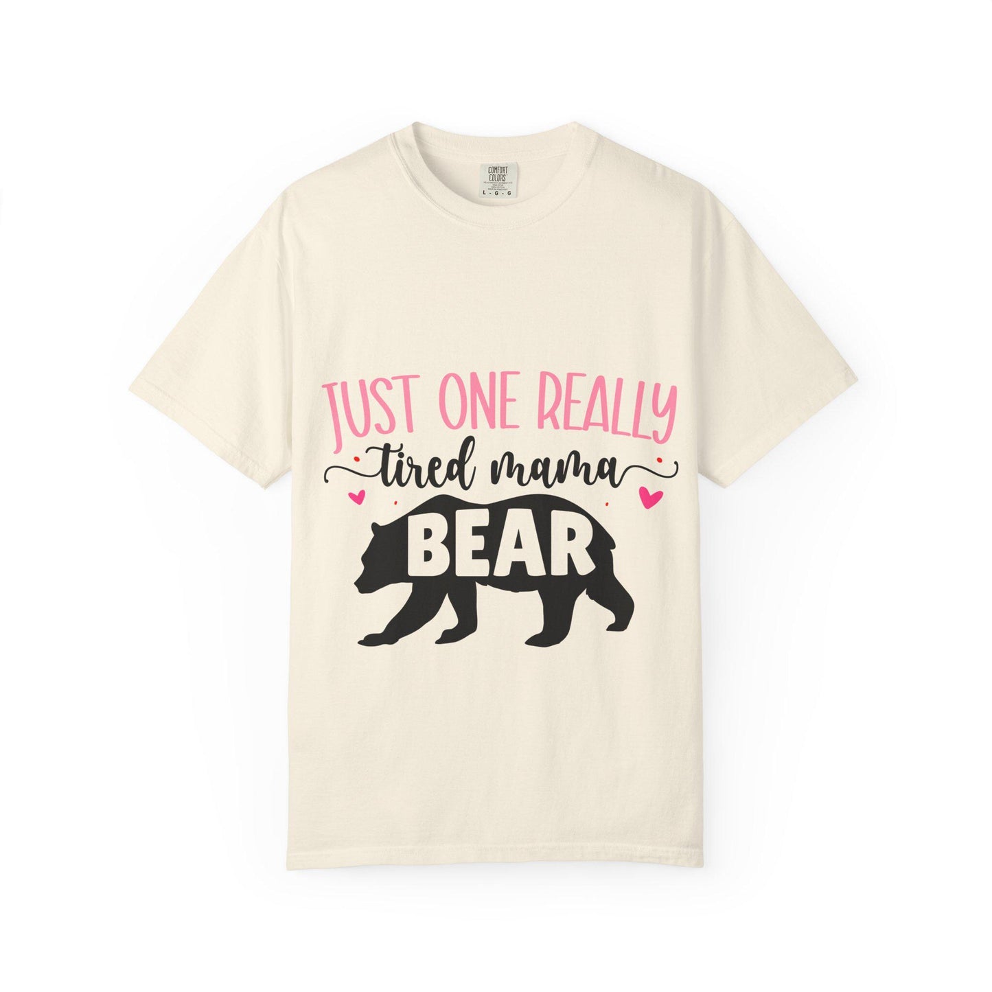 Cream Comfort Colors short sleeve t-shirt featuring the phrase “Just One Really Tired Mama Bear” in playful pink and black fonts. The design includes a bold black silhouette of a walking bear with the word “BEAR” in pink block letters inside the bear, and small pink hearts for added charm. A cozy, fun, and relatable shirt for moms, perfect for Mother’s Day, new moms, or as a comfy everyday mom life tee.